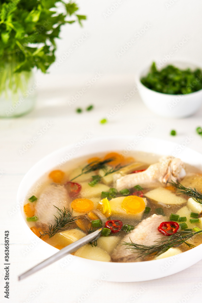 Chicken soup with fresh vegetables, chicken wings broth and young potatoes with onions and carrots, chopped green onions and parsley Chicken soup with fresh vegetables, chicken wings broth and young potatoes with onions and carrots, chopped green onions and parsley