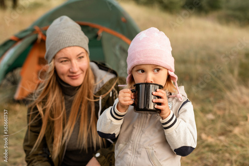 Mommy smiles at her baby girl while she s drinking from the mug photo