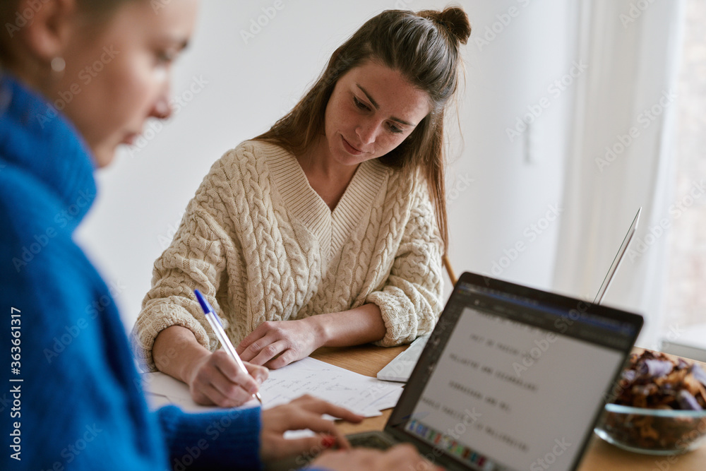 Students in sweaters using laptops for doing homework Students in sweaters using laptops for doing homework