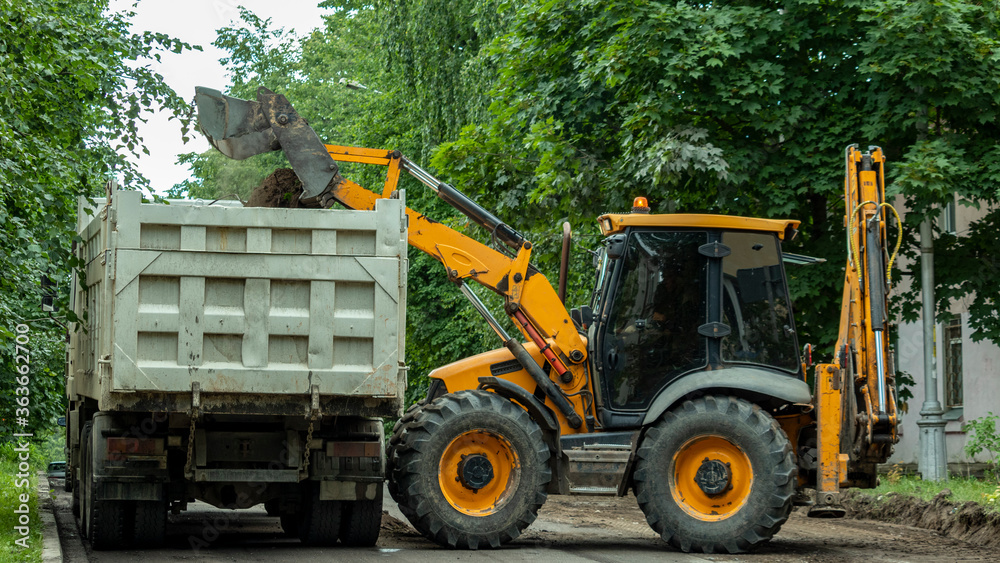 the tractor empties the earth into the body of the dump truck