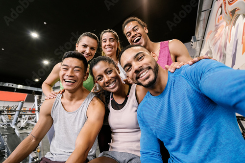 Interracial gym partners taking a selfie after workout at gym. photo