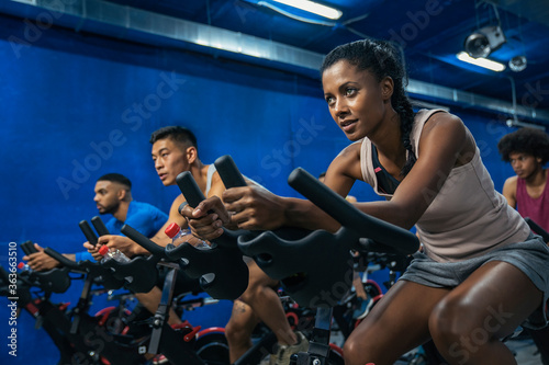 Group of sporty people training on exercise bikes together at gym.