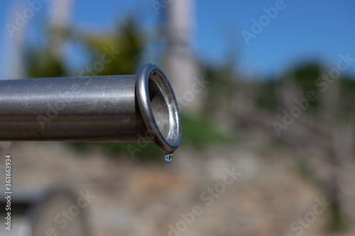 closeup of the last drop of water coming out a pipe simbolyzing draught, hot weather and climate change