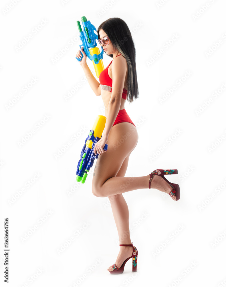 brunette girl with a water gun in a red swimsuit, slim and sexy brunette girl with a water gun in a red swimsuit, slim and sexy