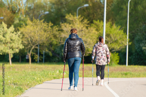 plus size women with nordic walking poles at the city park training to maintain health and fight overweight