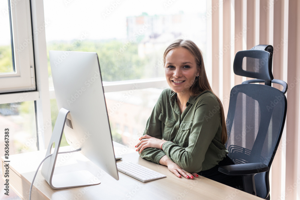 Portrait of a cheerful businesswoman sitting at the table in office Portrait of a cheerful businesswoman sitting at the table in office