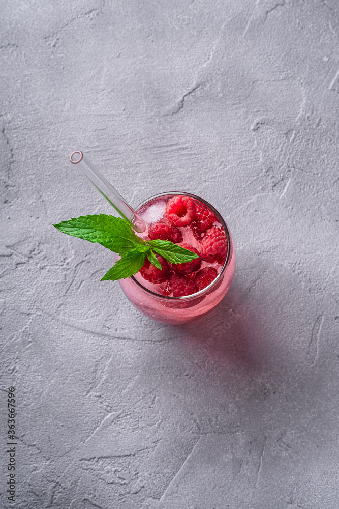 Fresh ice cold berry juice drink with mint, summer raspberry lemonade in glass with straws on stone concrete background, top view Fresh ice cold berry juice drink with mint, summer raspberry lemonade in glass with straws on stone concrete background, top view