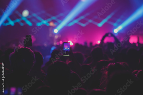 A crowded concert hall with scene stage lights, rock show performance, with people silhouette 