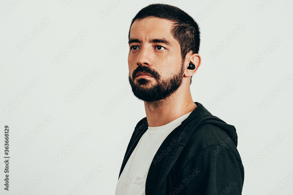 Obraz premium Portrait of a young bearded man wearing sports clothes and wireless earphones.