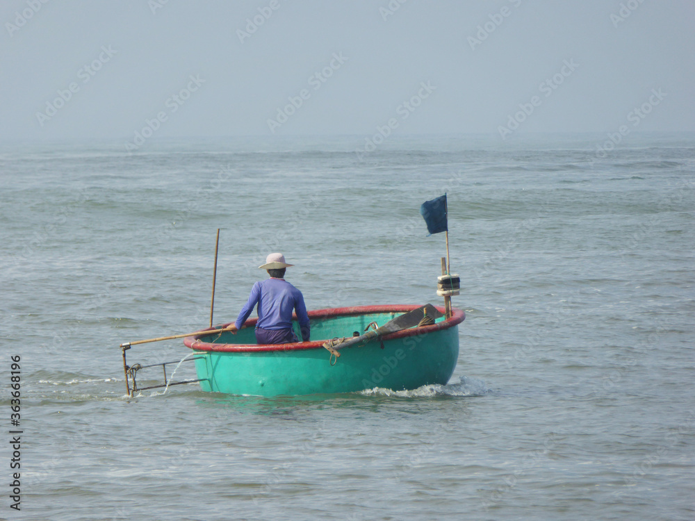 a vietnamese fisherman in a typical boat near Mui Ne