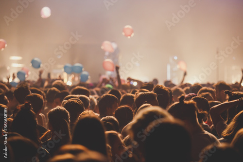 A crowded concert hall with scene stage lights, rock show performance, with people silhouette
