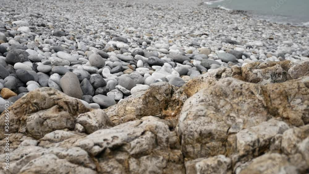 Rocky pebble stone shoreline with ocean waves background marine landscape close-up low wide dolly right Rocky pebble stone shoreline with ocean waves background marine landscape close-up low wide dolly right