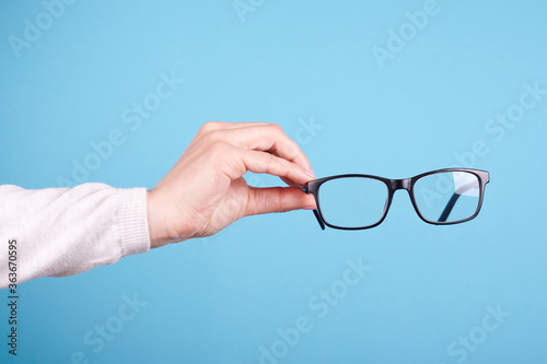 Glasses in a hand isolated on a blue background.