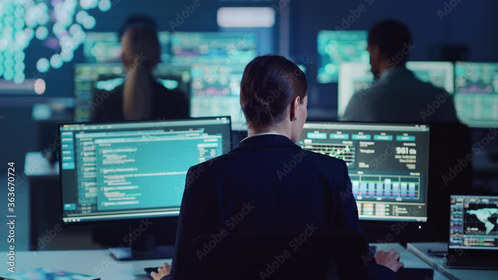 Confident Female Data Scientist Works on Personal Computer in Big Infrastructure Control and Monitoring Room with Neural Network. Woman Engineer in an Office Room with Colleagues. Confident Female Data Scientist Works on Personal Computer in Big Infrastructure Control and Monitoring Room with Neural Network. Woman Engineer in an Office Room with Colleagues.