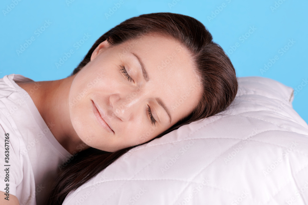 Brunette girl sleep on white pillow, closed eyes. Isolated on blue background. Brunette girl sleep on white pillow, closed eyes. Isolated on blue background.