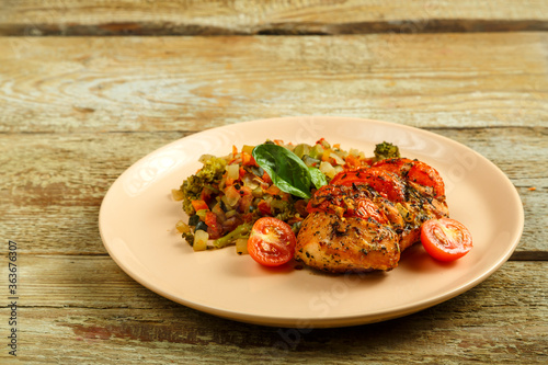 Baked chicken with tomatoes in spices with a side dish of frozen boiled vegetables.