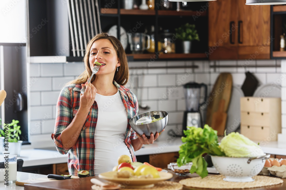 Beautiful pregnant woman preparing healthy meal with lots of vegetables at home