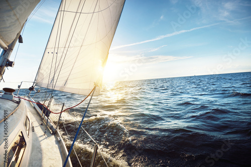 Canvas Print White sailboat in an open sea at sunset