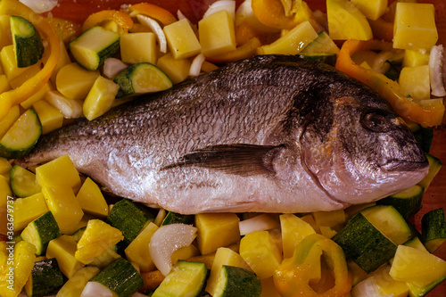 still life con pescado crudo con verduras cortadas en trozos listo para cocinar en el horno photo