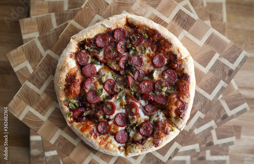 Delicious pizza with sausages lies wooden surface