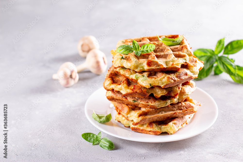 Zucchini waffle, zucchini fritters cooking on waffle maker, vegetarian zucchini waffles with basil on a plate. Copy space