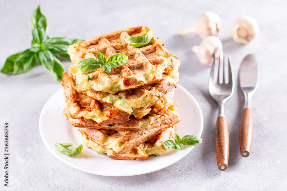 Zucchini waffle, zucchini fritters cooking on waffle maker, vegetarian zucchini waffles with basil and garlic in a plate on a light background