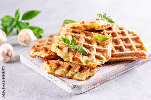 Zucchini waffle, zucchini fritters cooking on waffle maker, vegetarian zucchini waffles with basil and garlic on a white board