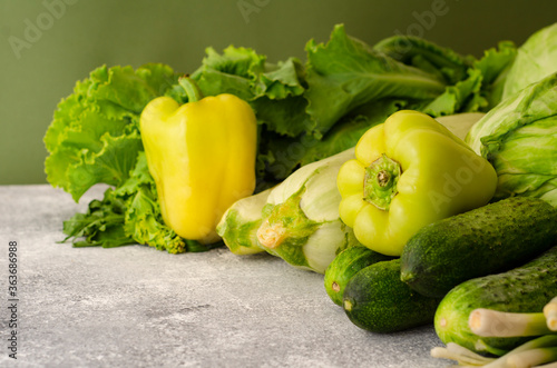 Healthy vegetarian food concept background, fresh green food selection for detox diet, raw cucumber, zucchini, cabbage, yellow pepper, salad and , top view
