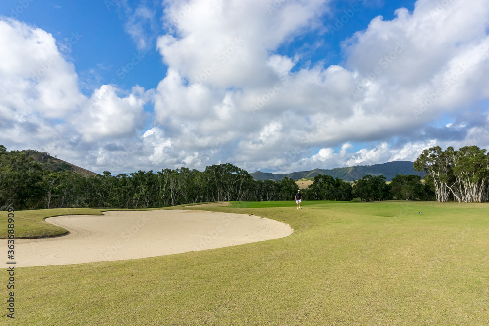 golf course in new caledonia with blue sky. Hills in the background
