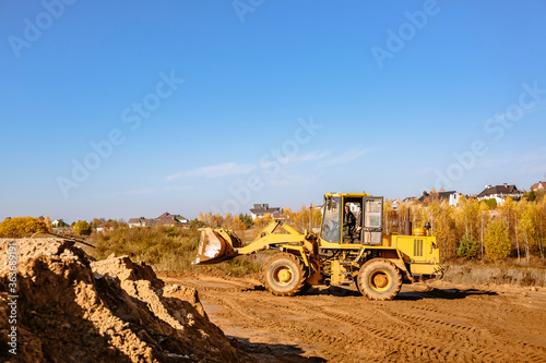 large yellow wheel loader aligns a piece of land for a new building. Preparation of the land for the auction. Leveling the landscape and adding sand for construction.