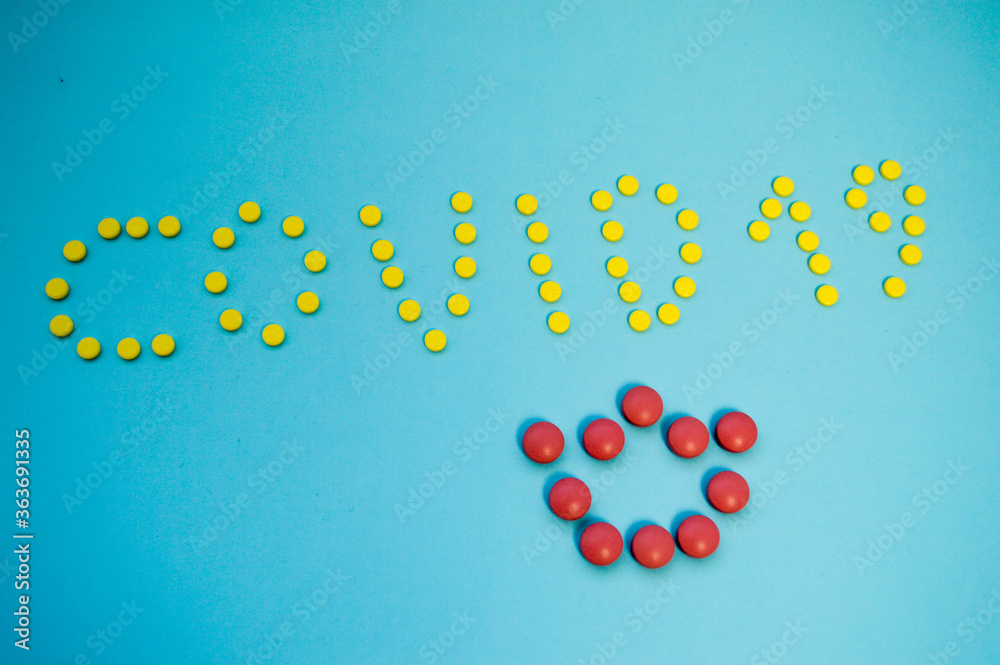 yellow bright pills laid out the inscription coronavirus 19 on a blue background. medications to treat a person and strengthen immunity. volumetric letters from tablets taken from above