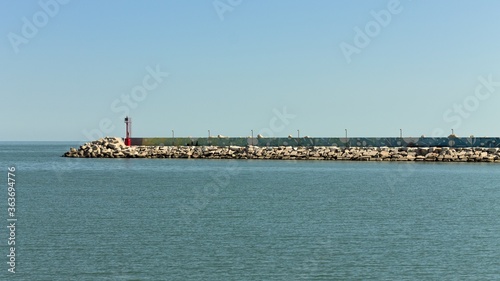 The pier of Pesaro harbor with breakwater cliffs, a colored wall and a small red lighthouse (Marche, Italy, Europe) © Tommaso