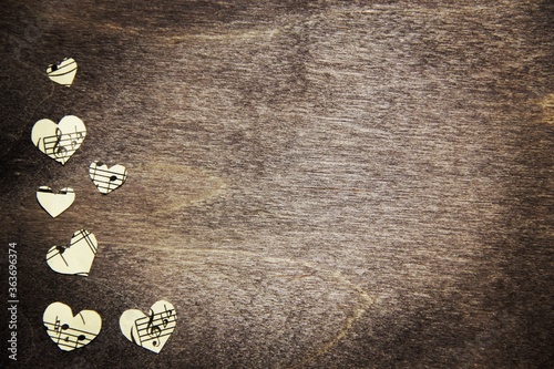 Notes and musical symbols on the Heart-shaped paper on a brown wooden background. Music love. 