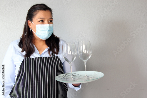 Latin woman waitress with tray and glasses working with face masks and protective gloves, new normal by covid-19 photo