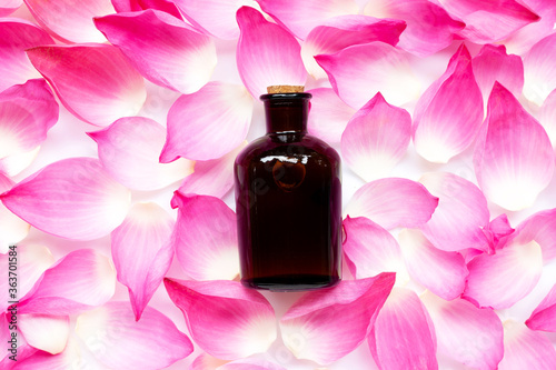 Essential oil bottle on pink lotus petals background.
