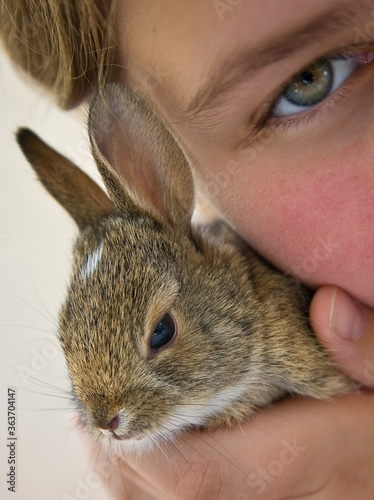 tightly cropped Little girl holding small rabbit close to face. We only see one eye of the little girl. Easter Bunny