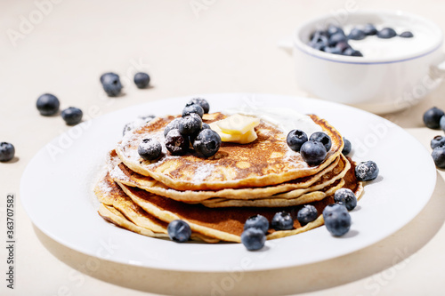 A stack of plain pancakes served with honey and blueberry
