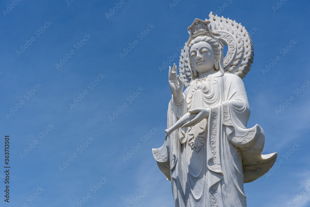 Detail of Lady Buddha statue in a Buddhist temple and blue sky background in Danang, Vietnam. Closeup, copy space