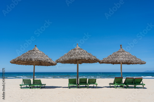Tropical sand beach and summer sea water with blue sky and straw umbrella. Travel and nature concept © OlegD