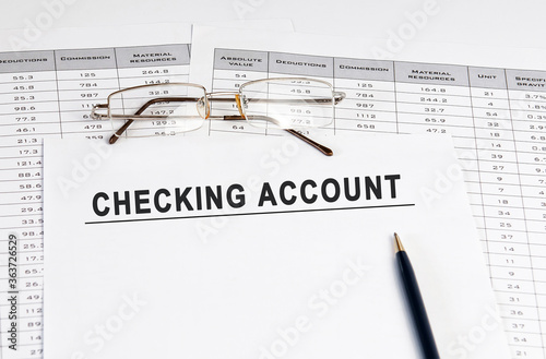 Checking account inscription on a sheet of paper against the background of glasses, pens and calculations.