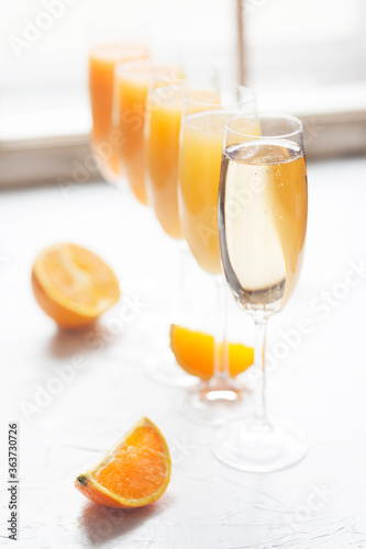 Fresh orange juice mimosas and champagne for brunch or bridal shower next to a window in natural light.  Arranged from from darkest to lightest (ombre effect with most orange juice to least)
