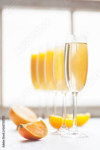 Fresh orange juice mimosas and champagne for brunch or bridal shower next to a window in natural light.  Arranged from from darkest to lightest (ombre effect with most orange juice to least)