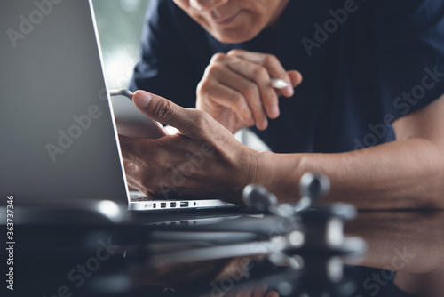 asian doctor using mobile phone working on laptop computer for telemedicine or teleconference 