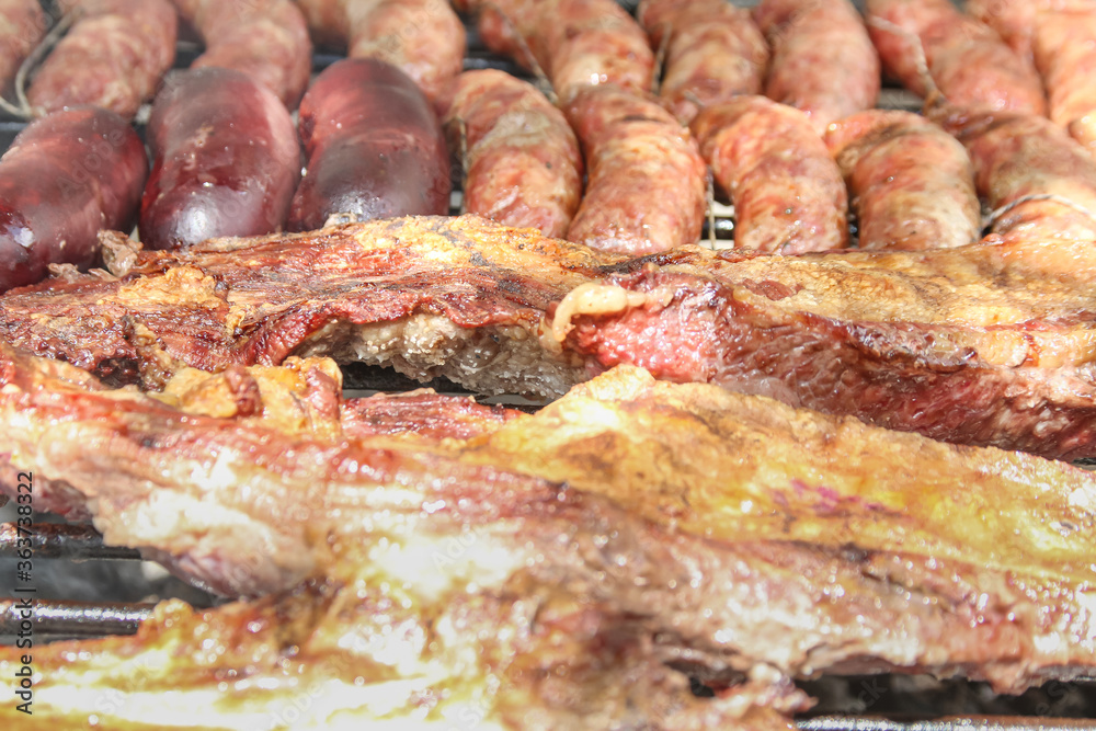 Different cuts of beef and pork and sausages on a barbecue