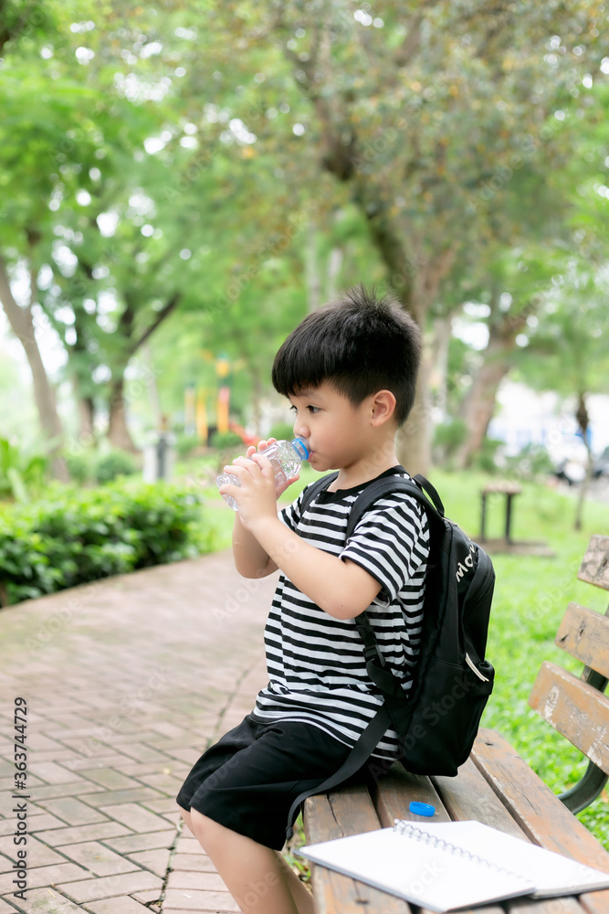 Cute little boy drinking mineral water from the plastic bottle in the park Cute little boy drinking mineral water from the plastic bottle in the park