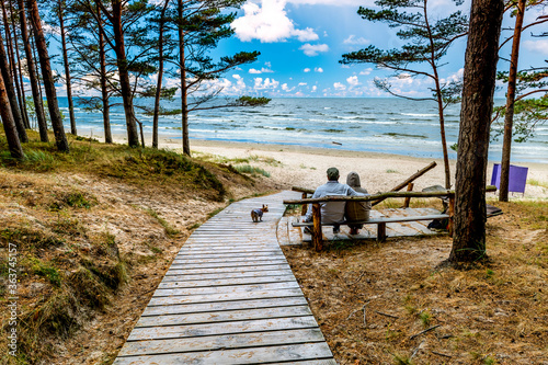 Happy couple of seniors are resting on wooden bench and  looking at the dista...