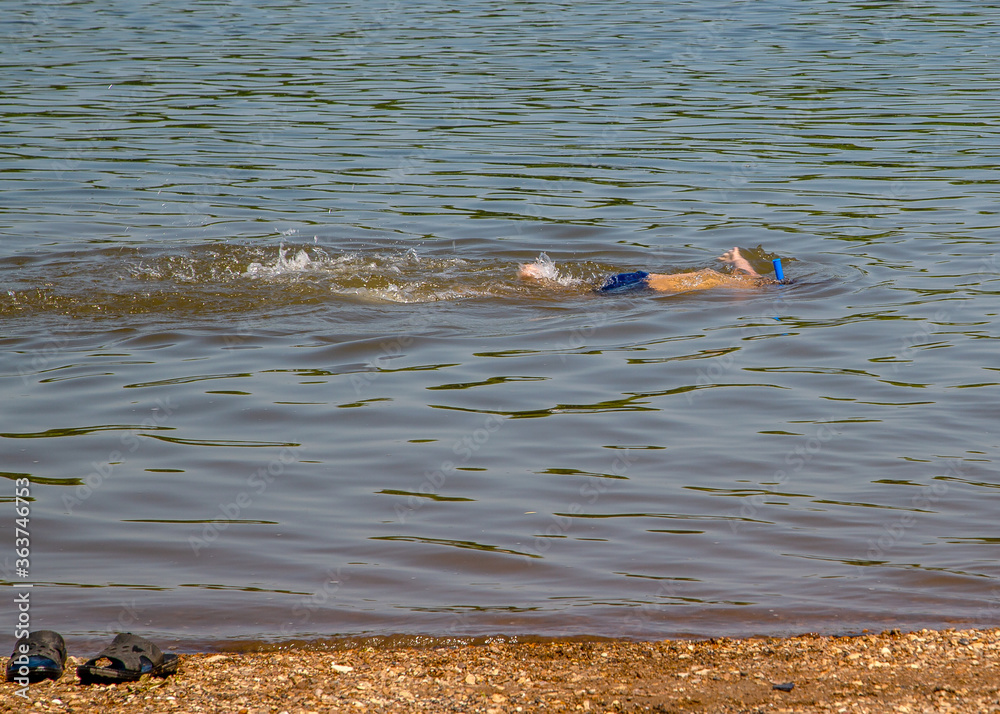 Obraz premium boy with snorkel and diving mask explores the bottom near the shore