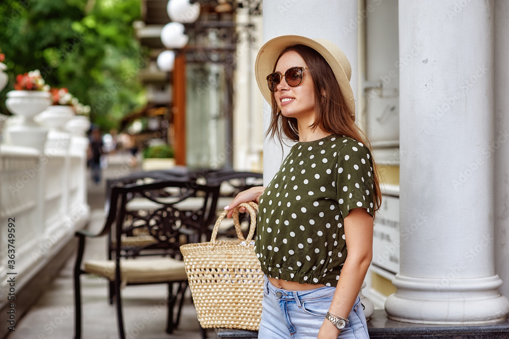 Portrait of a young beautiful woman in a straw hat on the street of a European city