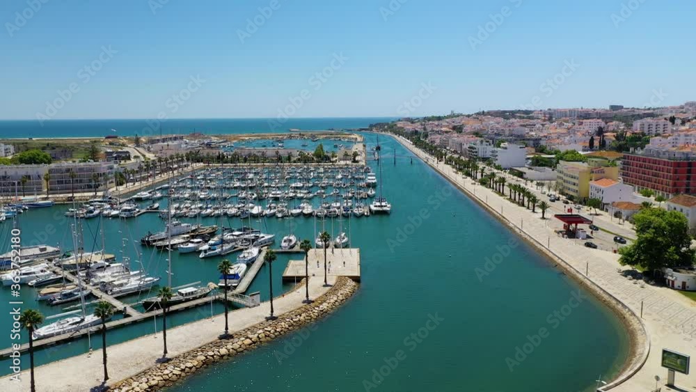 Aerial view over the Marina de Lagos and traffic on a bridge, bright, sunny day, in Algarve, Portugal - reverse, drone shot Aerial view over the Marina de Lagos and traffic on a bridge, bright, sunny day, in Algarve, Portugal - reverse, drone shot
