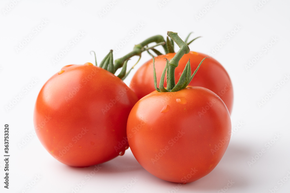 Fresh tomatoes on a green stem on white